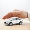 Eine schützende Hand über einem Spielzeug-Auto