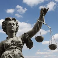 Justitia-Statue vor blau-weißem Himmel