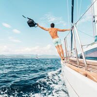Ein Mann steht auf einem Boot auf offenem Meer und genießt die Freiheit.